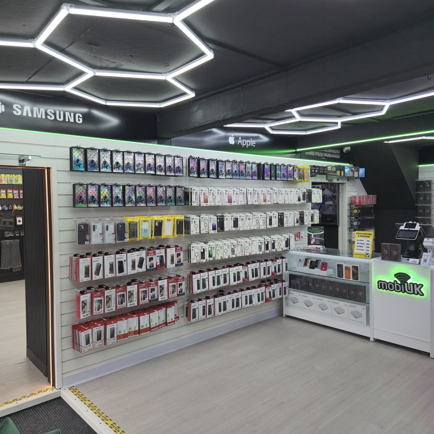 Inside mobiUK phone shop in Accrington — Samsung and Apple cases wall with hexagonal lighting